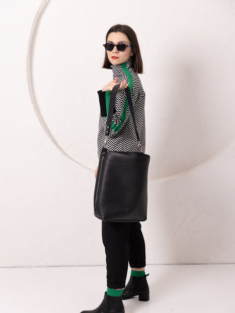 3. Side view of woman with ADDISON Leather Tote in black, highlighting strap length and leather texture