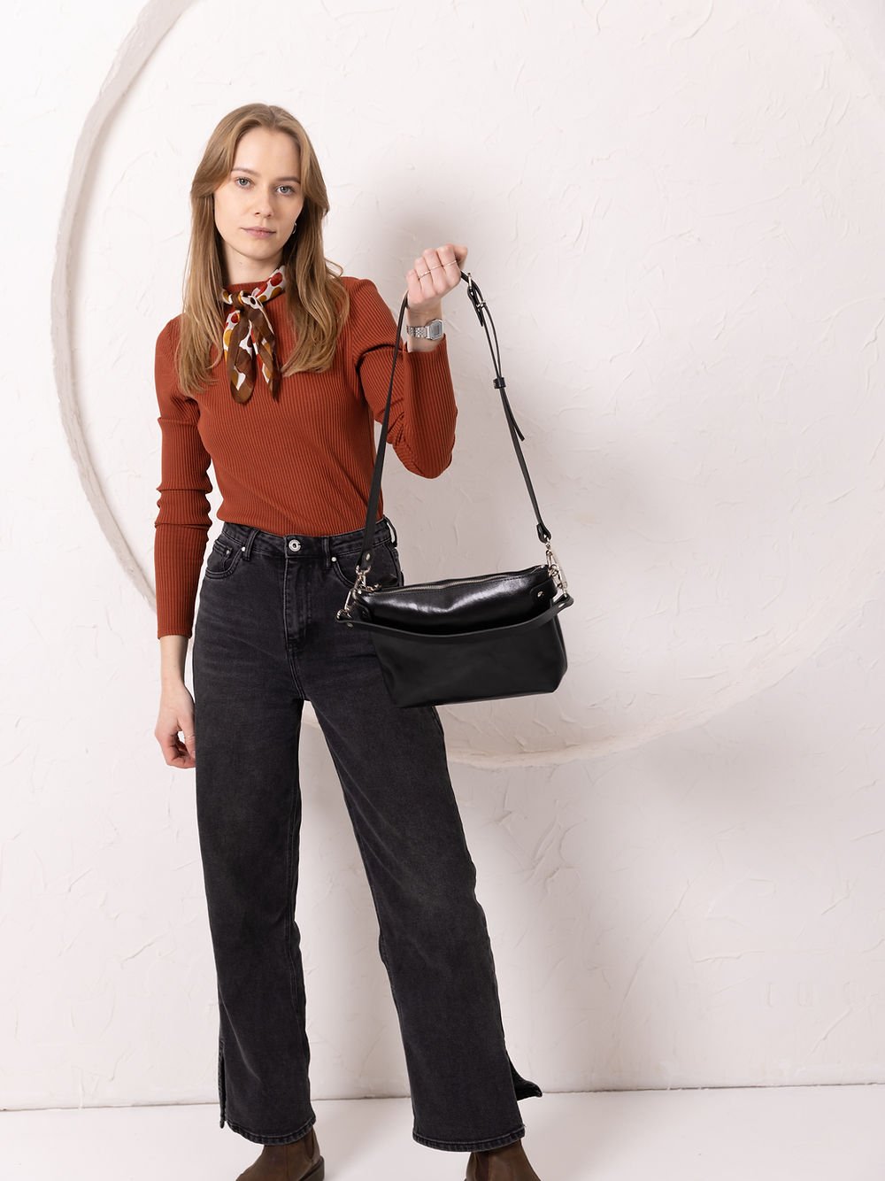 12. Women's black TOMMY leather bag by TOKS VISOKS held by model in studio setting