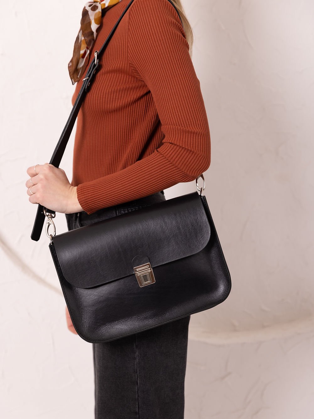 2. Close-up of woman holding TOKS VISOKS ASTORIA black leather handbag with old-fashioned buckle