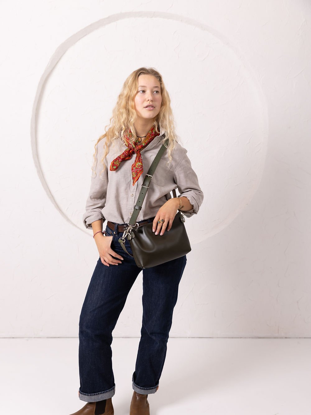 6. Women's TOMMY leather bag in dirty green worn crossbody, styled with casual outfit in studio setting