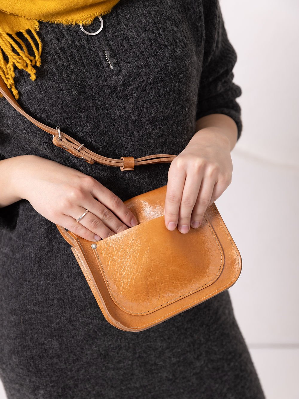 4. Close-up of woman opening TOKS VISOKS RUBY Purse in caramel leather, showing magnet buckle