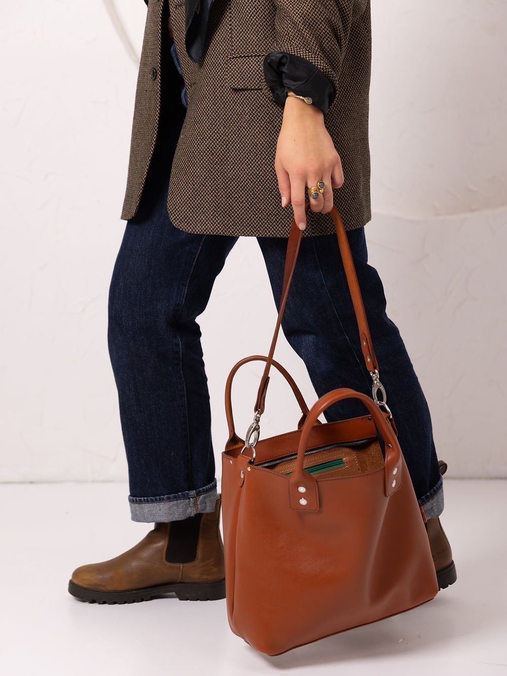 6. Side view of woman walking with TOKS VISOKS MIGLE leather handbag in ginger, demonstrating functionality