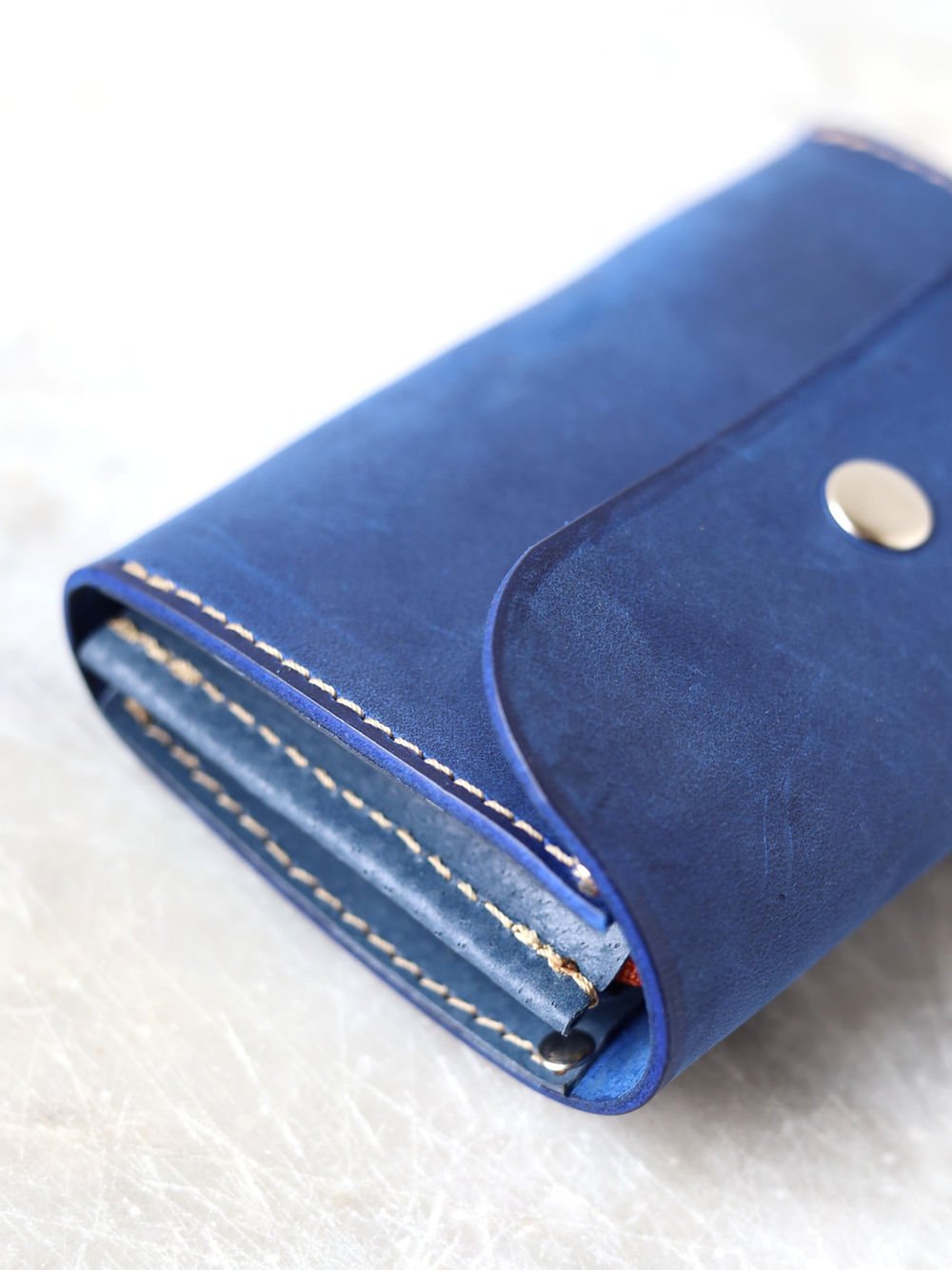 5. Detailed view of blue TOKS VISOKS FRIDAY Wallet, focusing on button clasp and leather finish