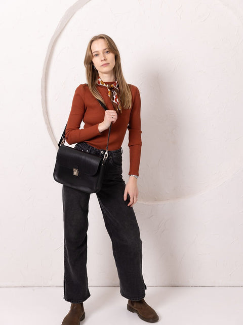 1. Woman wearing TOKS VISOKS ASTORIA black leather handbag with old-fashioned buckle in lifestyle setting