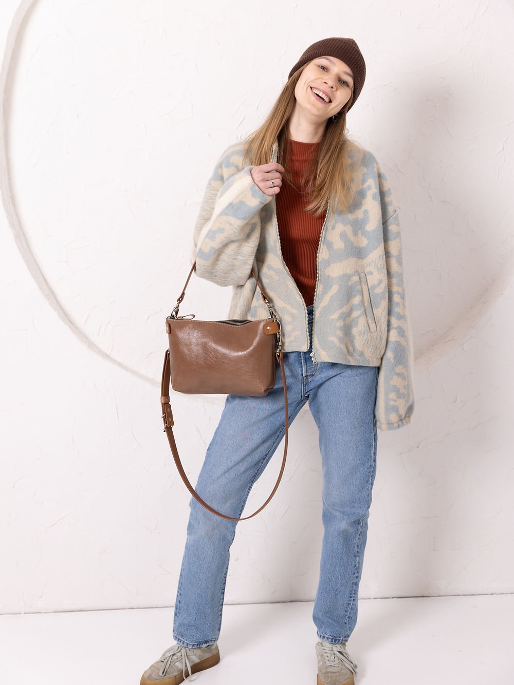 7. Woman smiling with TOKS VISOKS TOMMY leather bag in cappuccino, styled with casual attire