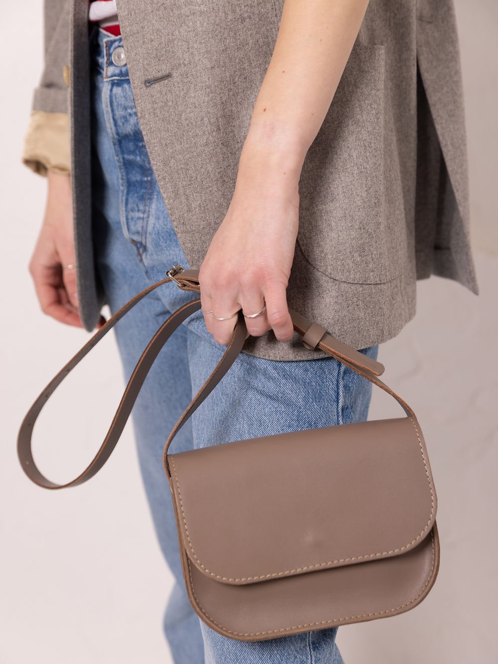 3. Close-up of woman holding TOKS VISOKS RUBY Purse in beige, showing adjustable strap and recycled leather