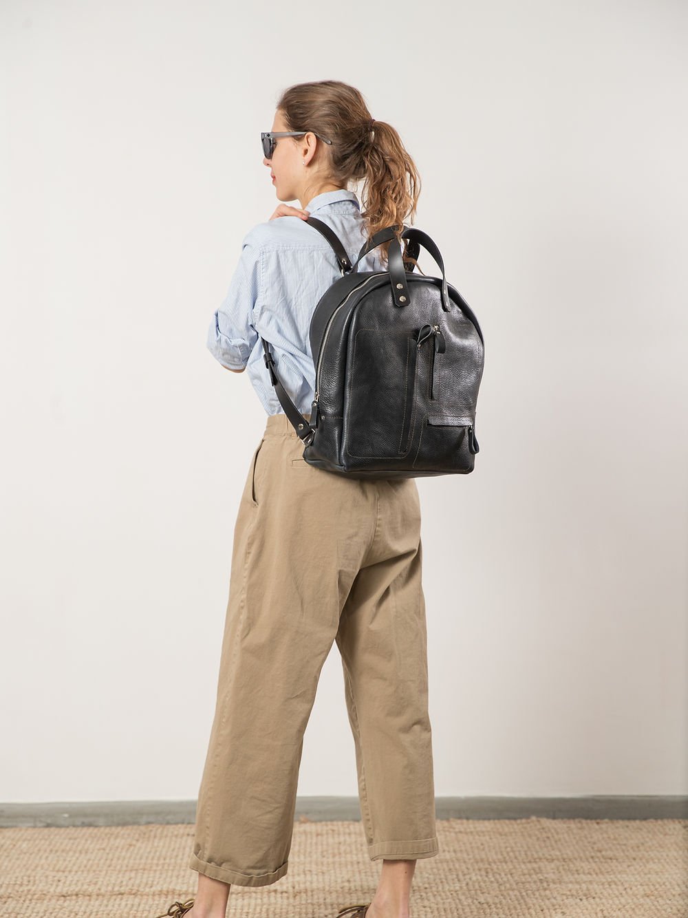 8. Woman wearing TOKS VISOKS GORDON Backpack in dark denim, shown from the back, emphasizing fit and style