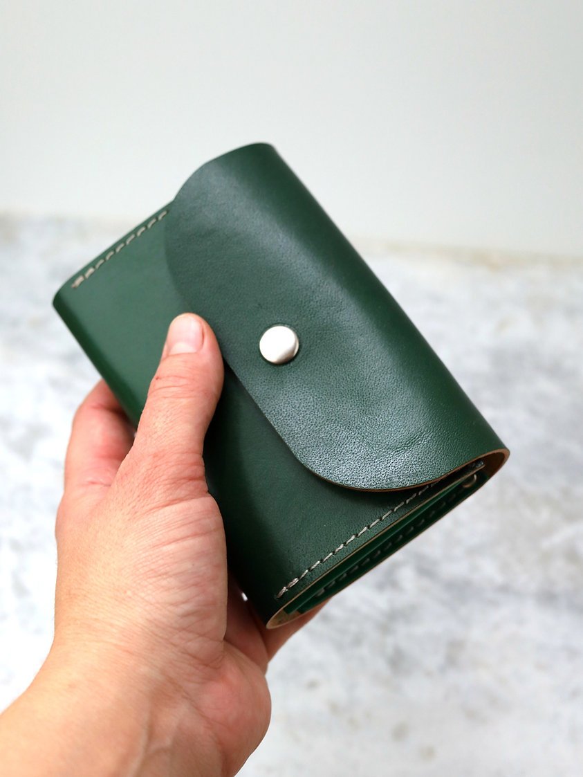 2. Close-up of the FRIDAY Wallet in green recycled leather, highlighting the secure snap closure