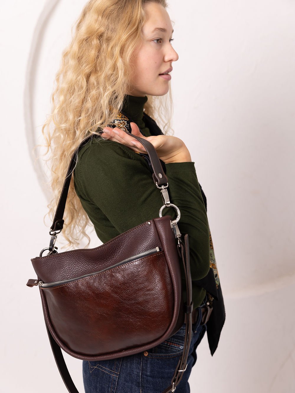 5. Side view of woman with TOKS VISOKS STELLA leather handbag in brown and cognac, showing zipper detail in studio