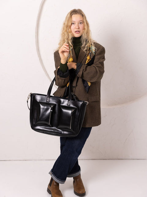 3. Women's black AMBER handbag by TOKS VISOKS, worn with a brown coat and jeans, shown in a studio setting
