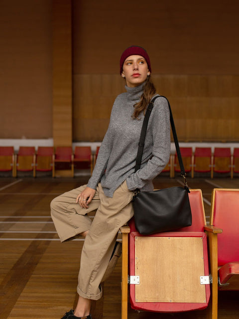 5. Woman posing with TOKS VISOKS ROBIN large black leather handbag, emphasizing luxurious texture and clean design