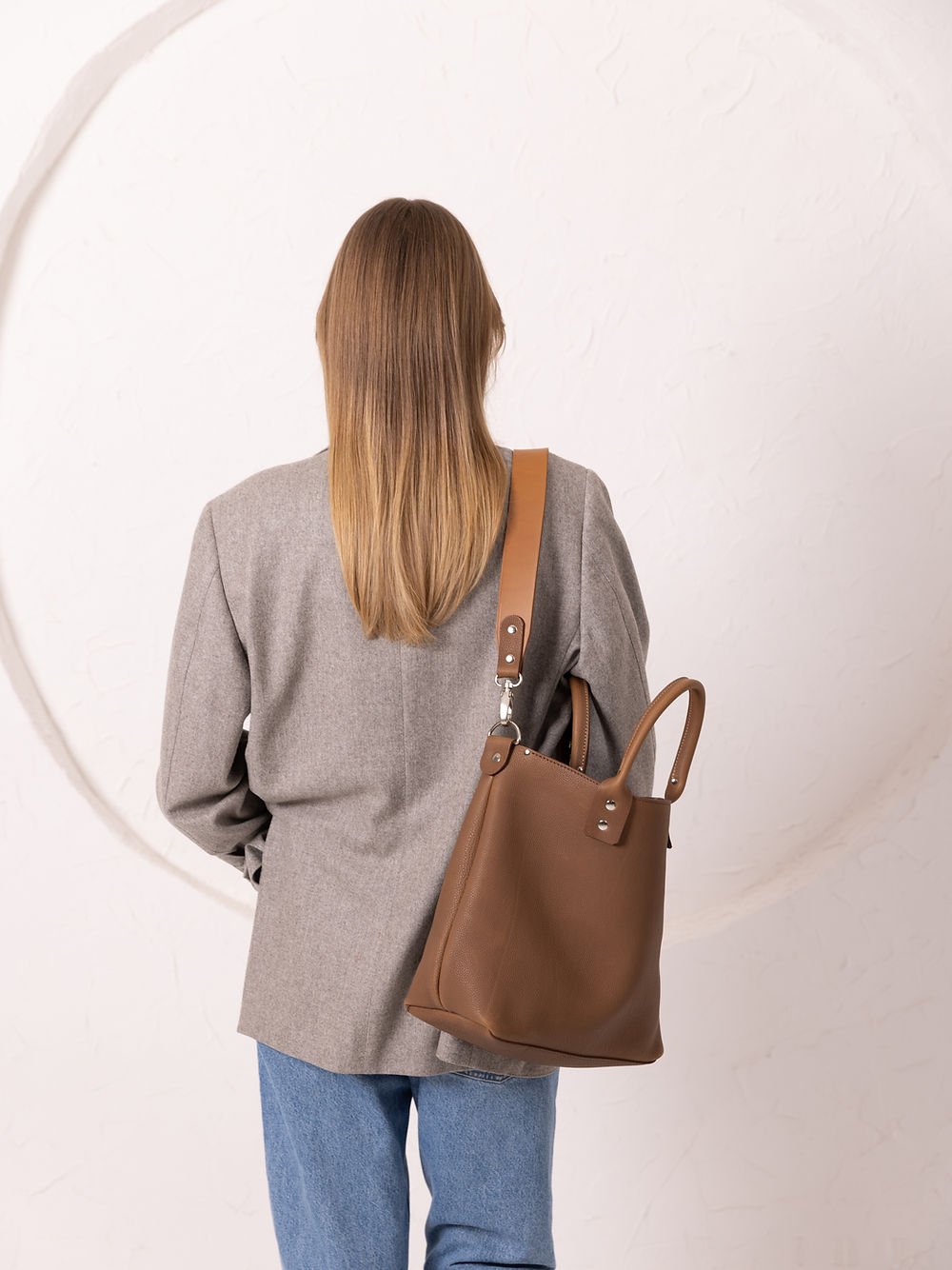 9. Back view of woman with MIGLE Leather Handbag in cappuccino by TOKS VISOKS, showing long strap