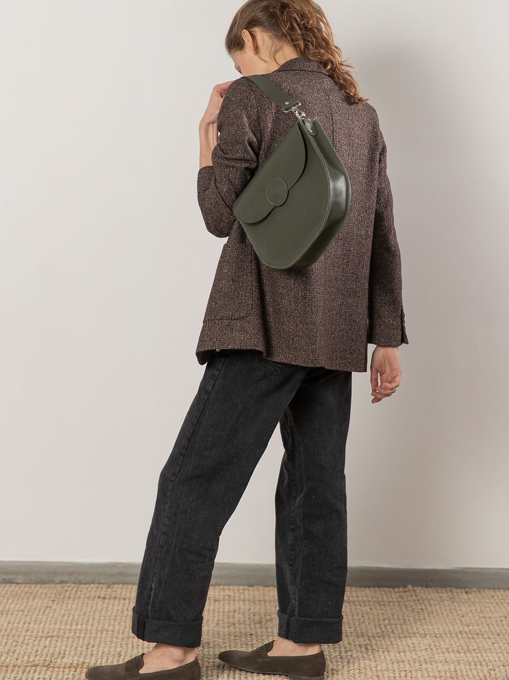 3. Back view of woman wearing TOKS VISOKS FIONA Handbag in faded green, showcasing shoulder strap