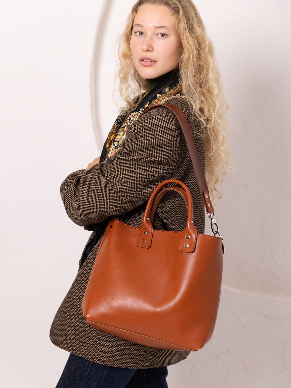 4. Woman wearing TOKS VISOKS MIGLE leather handbag in ginger over shoulder, highlighting versatility