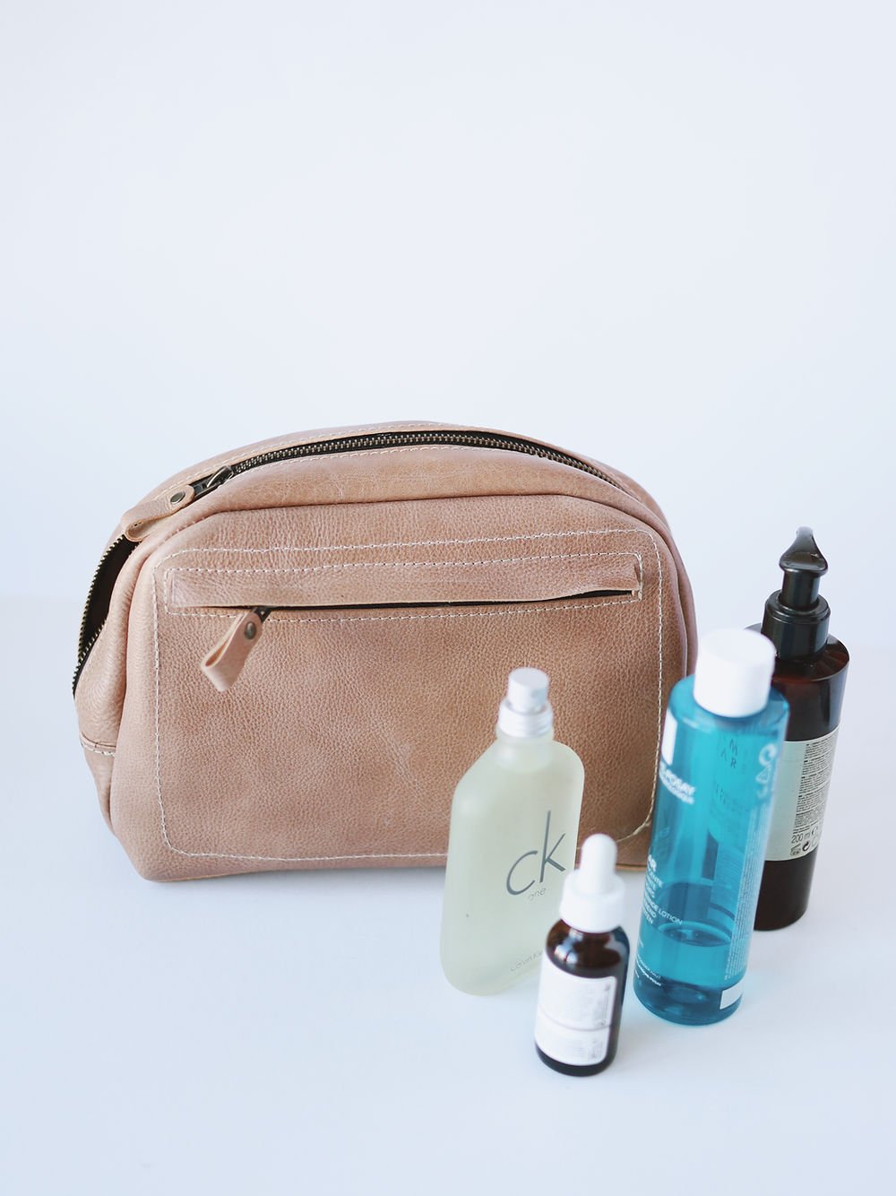 2. Beige leather DOUGLAS Toiletry Bag by TOKS VISOKS with beauty products, highlighting spacious design