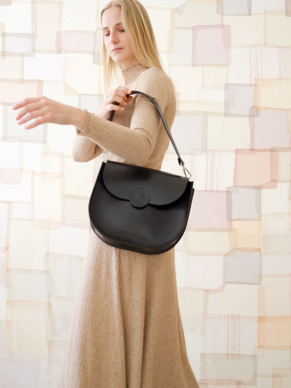 5. Woman displaying TOKS VISOKS FIONA Handbag in black, highlighting seamless design and magnet closure