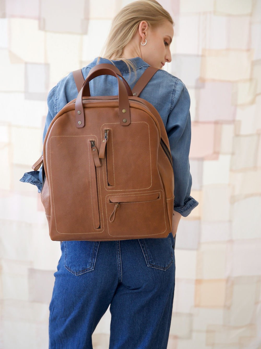 1. Woman wearing TOKS VISOKS GORDON Backpack in Capuccino, shown from the back in lifestyle setting