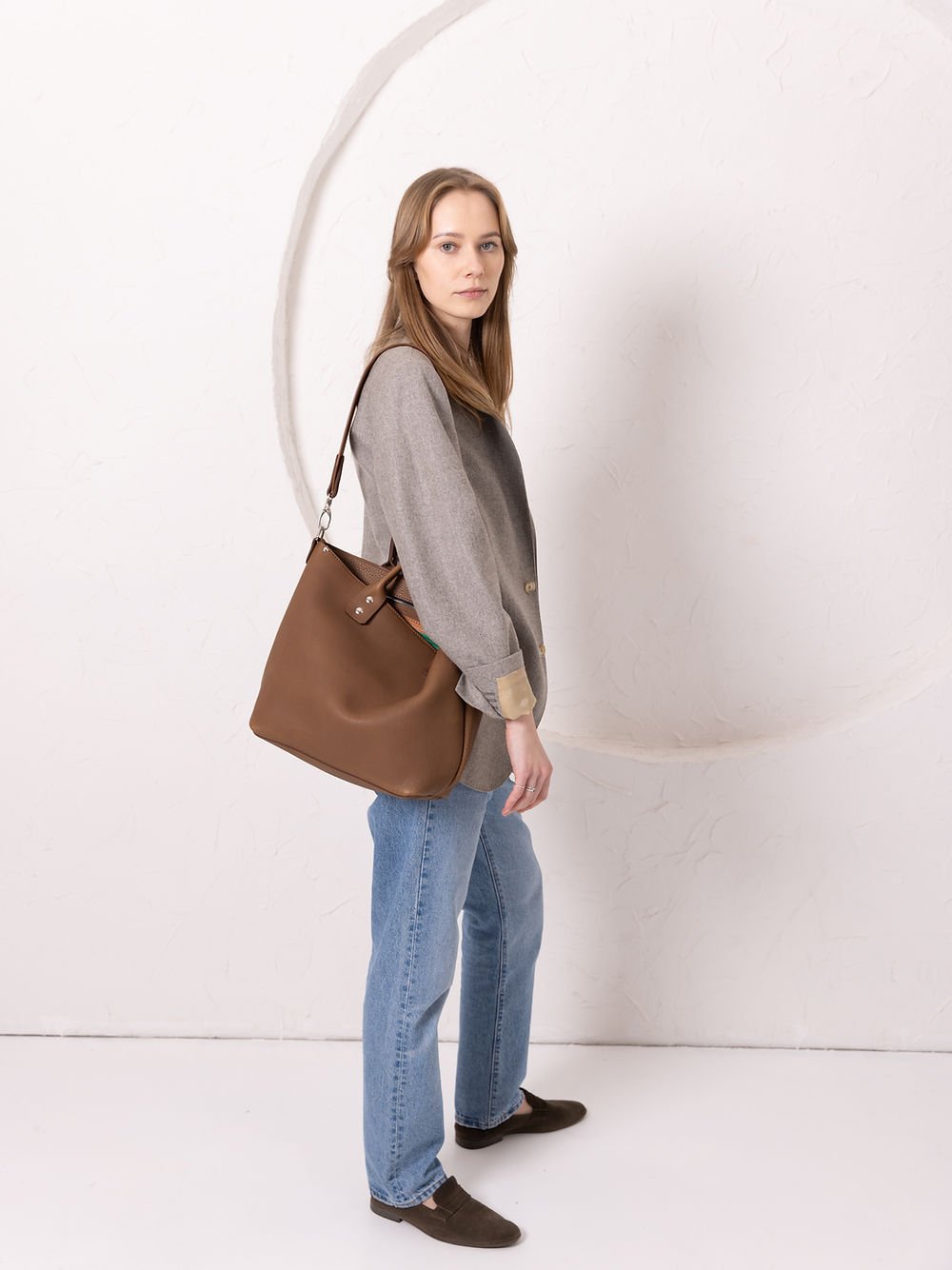 3. Side view of woman carrying MIGLE Leather Handbag in cappuccino by TOKS VISOKS, styled casually