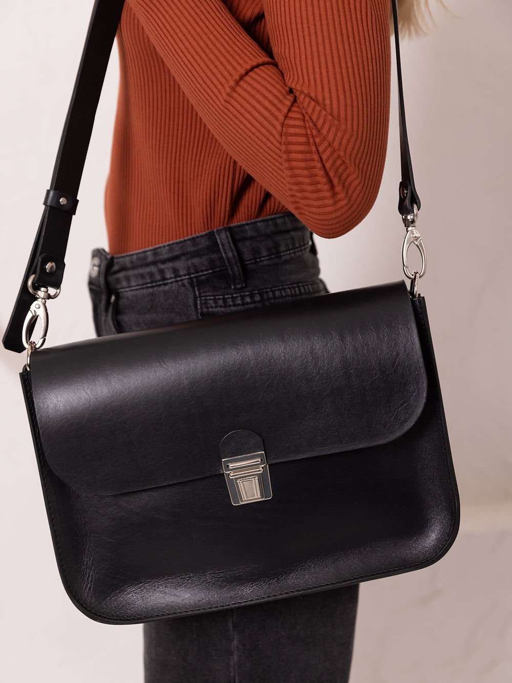 3. Side view of TOKS VISOKS ASTORIA black leather handbag with old-fashioned buckle on woman's shoulder