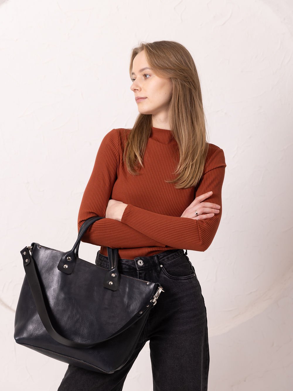 2. Women's MIGLE Leather Handbag in Dark Denim by TOKS VISOKS, held by short handles in lifestyle setting