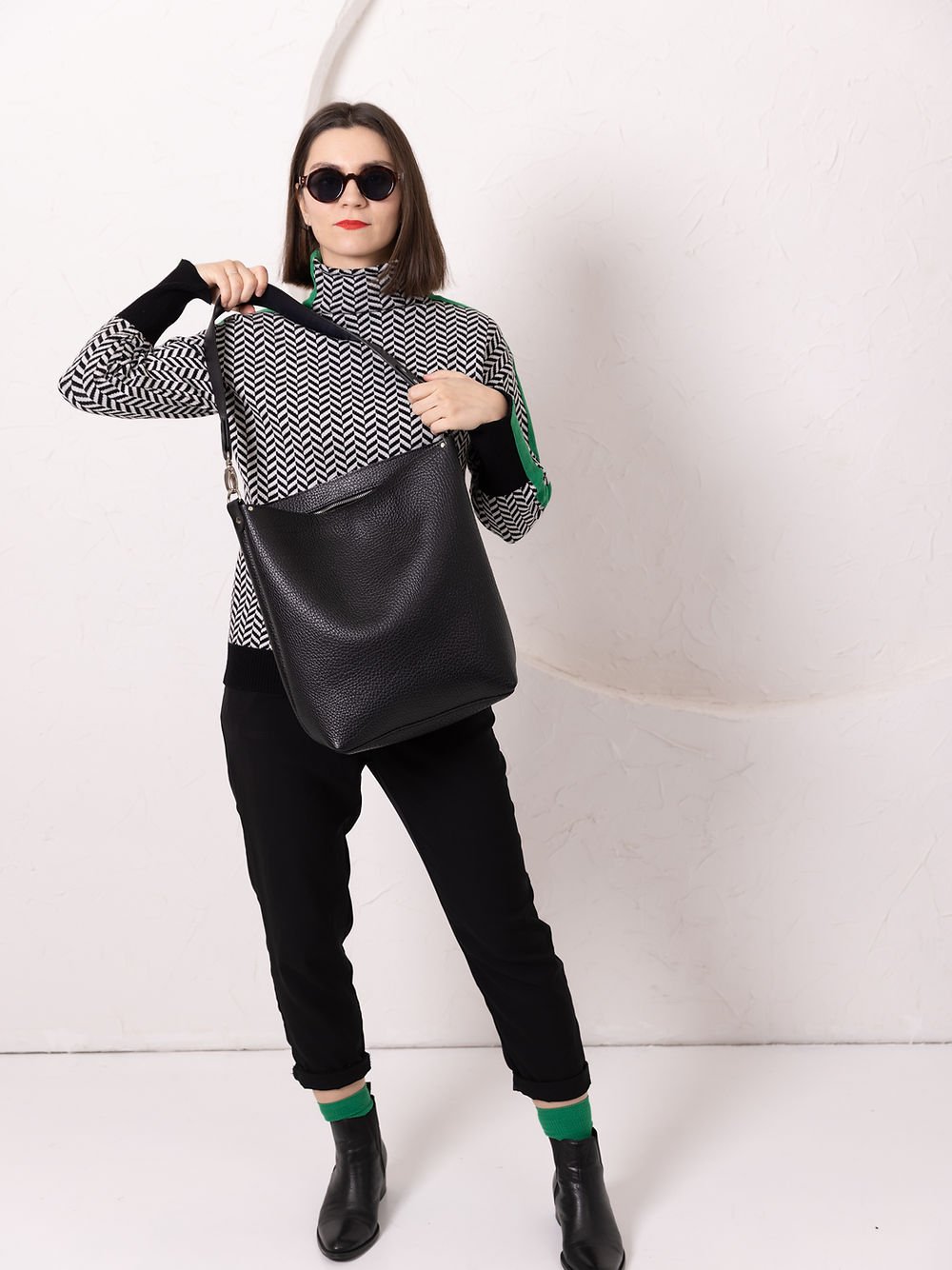 5. Woman holding ADDISON Leather Tote in black, demonstrating versatile carrying style