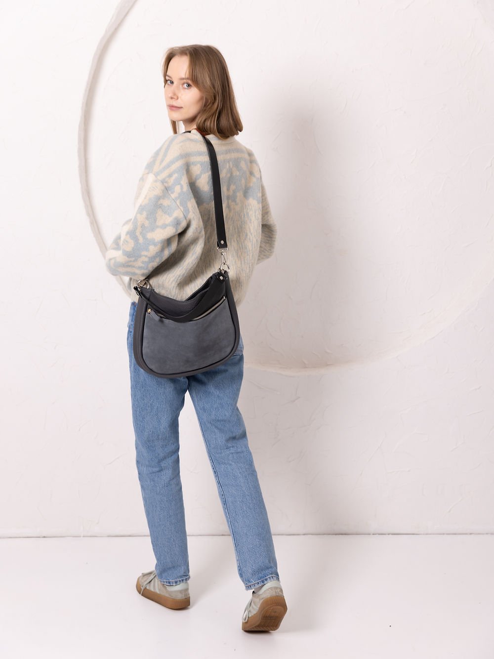 1. Woman wearing TOKS VISOKS STELLA grey leather handbag with suede detail, styled with casual outfit in lifestyle setting