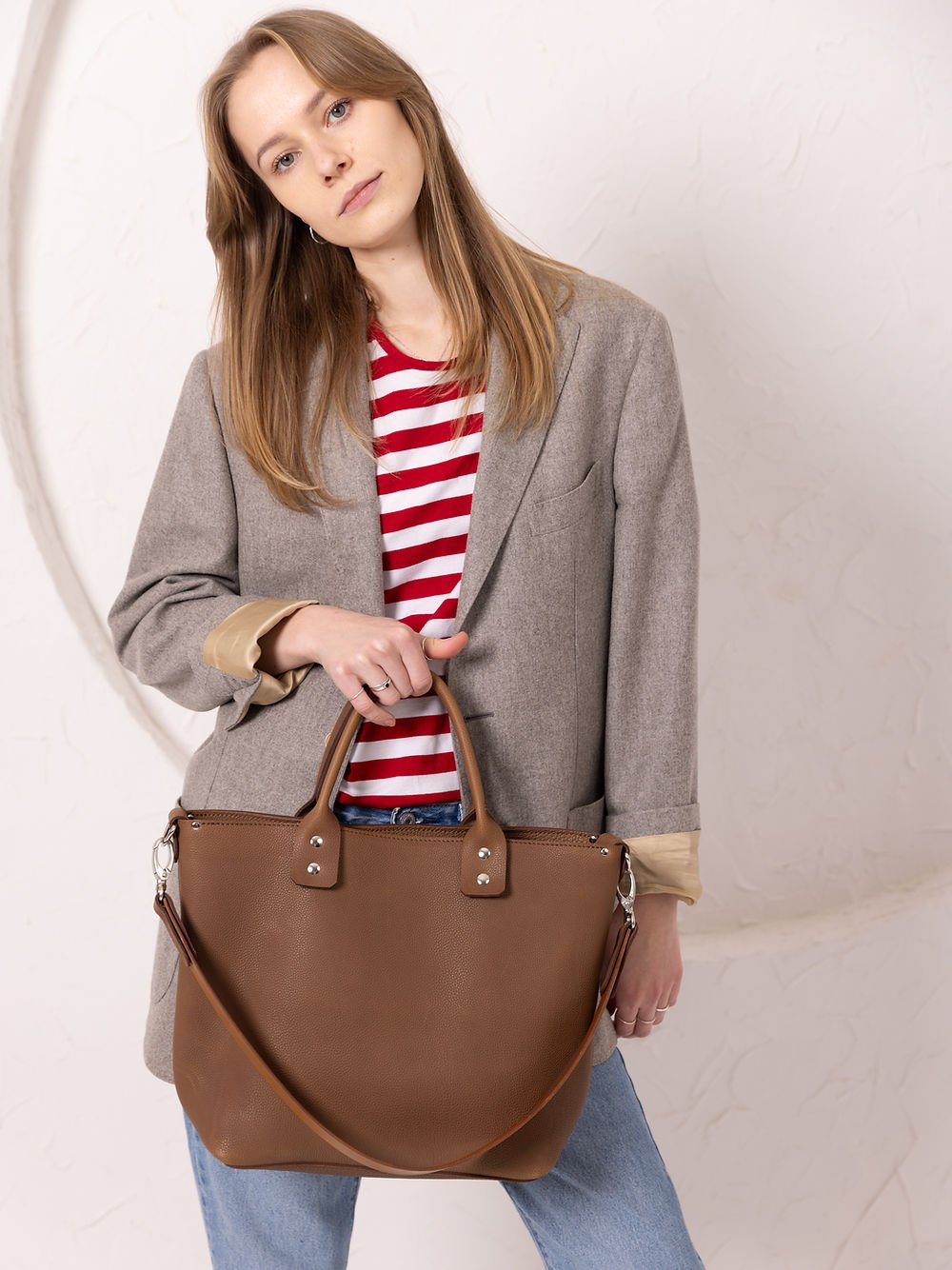5. Woman holding MIGLE Leather Handbag in cappuccino by TOKS VISOKS, showcasing long strap