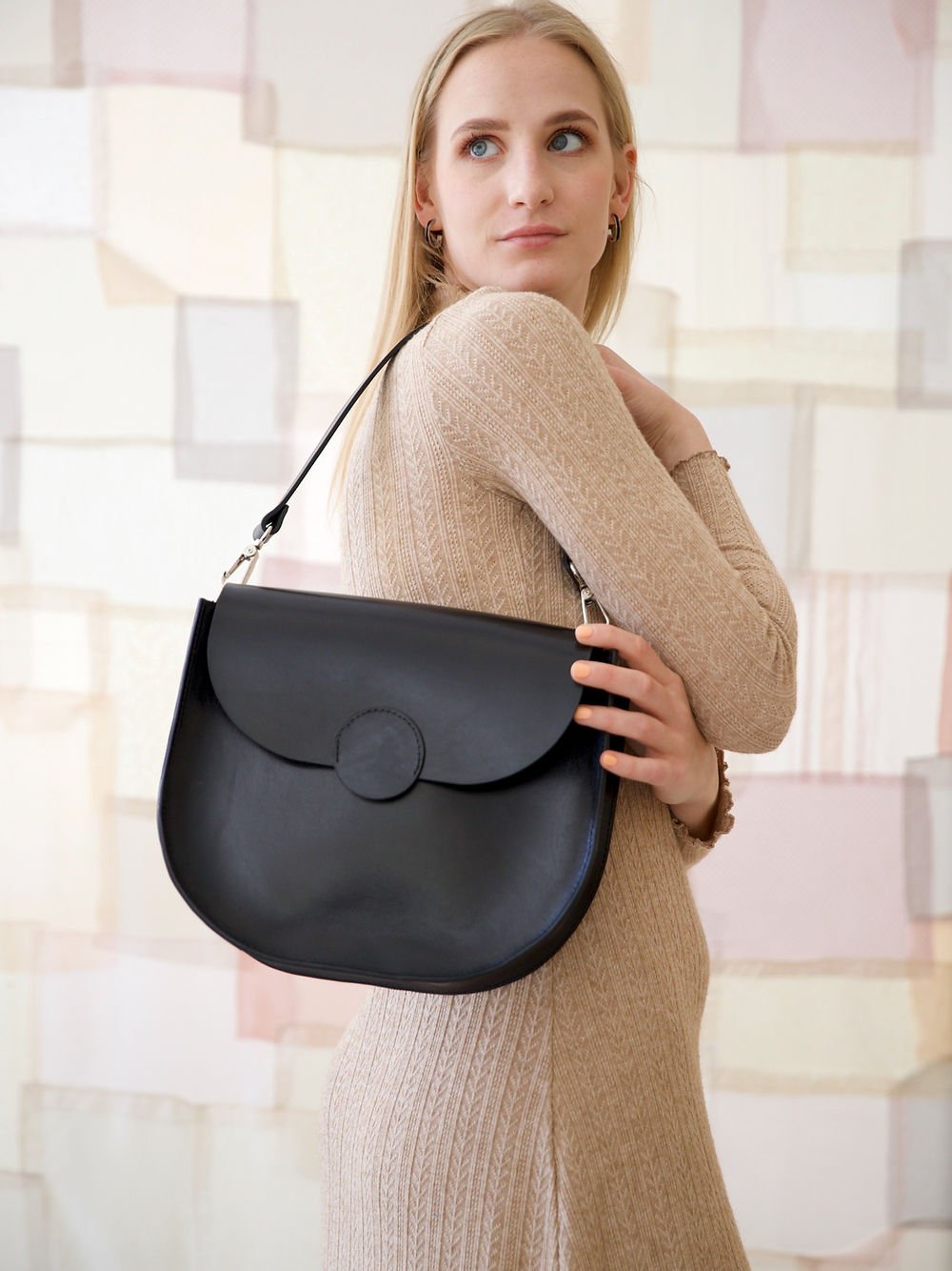 7. Woman holding TOKS VISOKS FIONA Handbag in black, styled with a beige dress, highlighting chic look