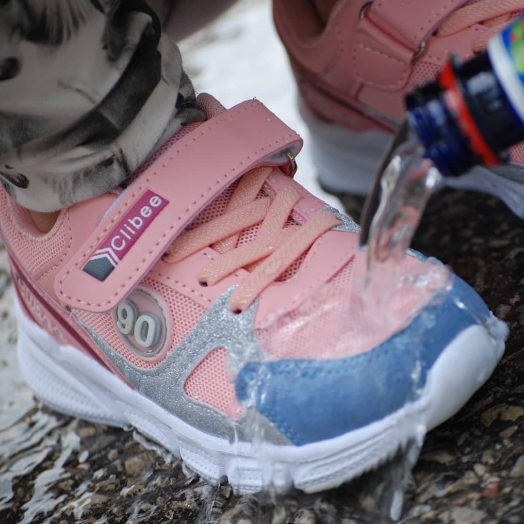 1. Pink and blue children's sneaker with water being poured over, highlighting GoGoNano's water-repellent effect