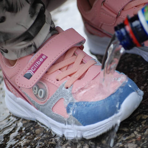 1. Pink and blue children's sneaker with water being poured over, highlighting GoGoNano's water-repellent effect