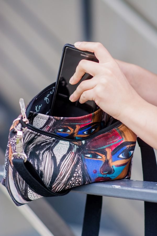 6. Close-up of women's shoulder bag with mermaid artwork by Dovilė Aleksonė, showing phone being placed inside