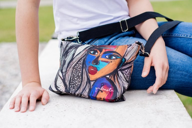 7. Women's shoulder bag with mermaid artwork by Dovilė Aleksonė, shown on lap with casual outfit