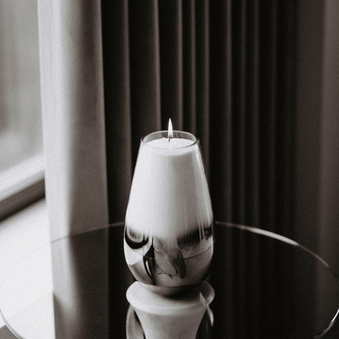 4. Black and white image of Candledust powdered candle in a tall glass container on a reflective surface