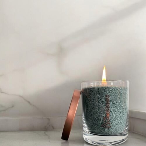 1. Candledust unscented powder candle in emerald glass with metal lid, lit on marble surface