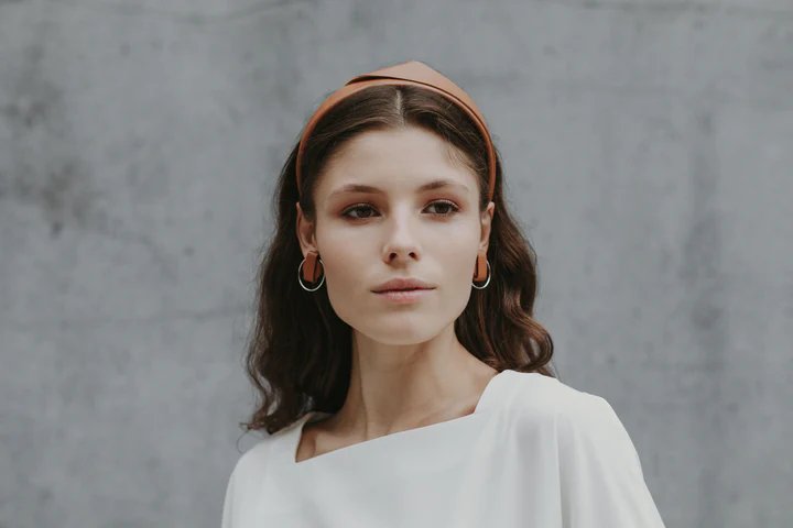 1. Women's caramel brown handmade leather headband by Gerda Retter Design, worn by model in lifestyle setting