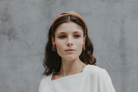 1. Women's caramel brown handmade leather headband by Gerda Retter Design, worn by model in lifestyle setting