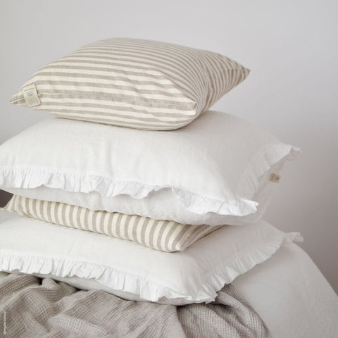 5. Stack of white and striped linen pillowcases with frills on a bed, showcasing variety