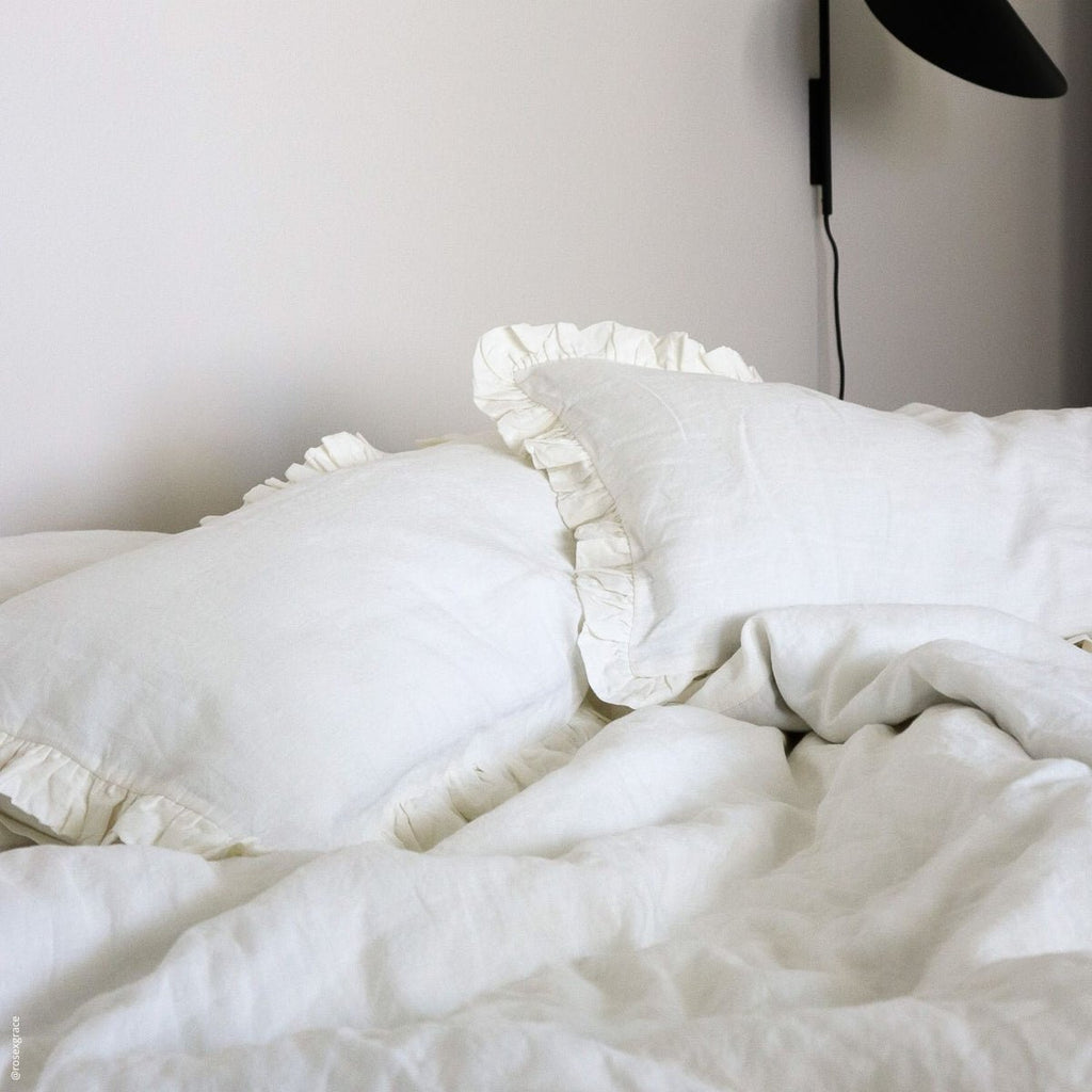 6. White frilled linen pillowcases on a bed with a black lamp, creating a serene bedroom atmosphere