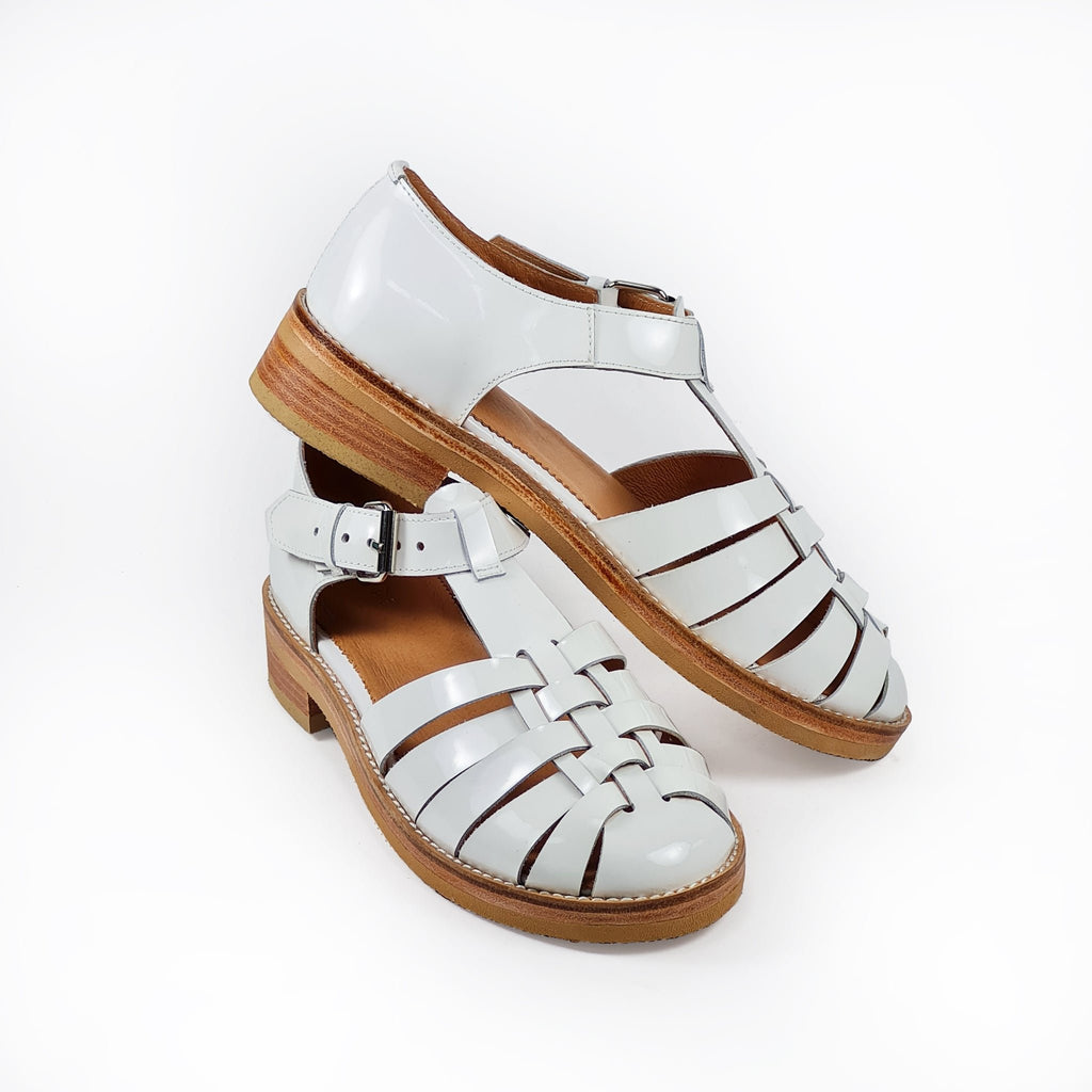7. Angled view of white leather fisherman sandals by Daz Studio, showing stacked leather heel and buckle detail