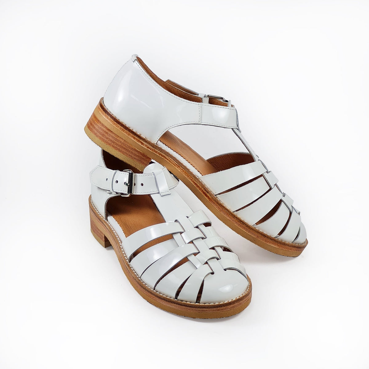 7. Angled view of white leather fisherman sandals by Daz Studio, showing stacked leather heel and buckle detail