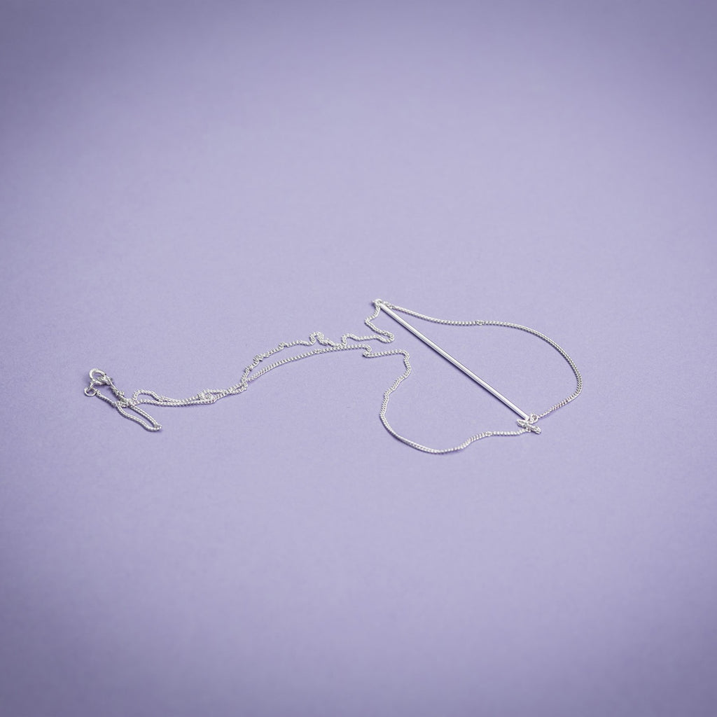 3. Flat lay of Maarja Palu Necklace SWING in silver on purple background, highlighting chain and bar design