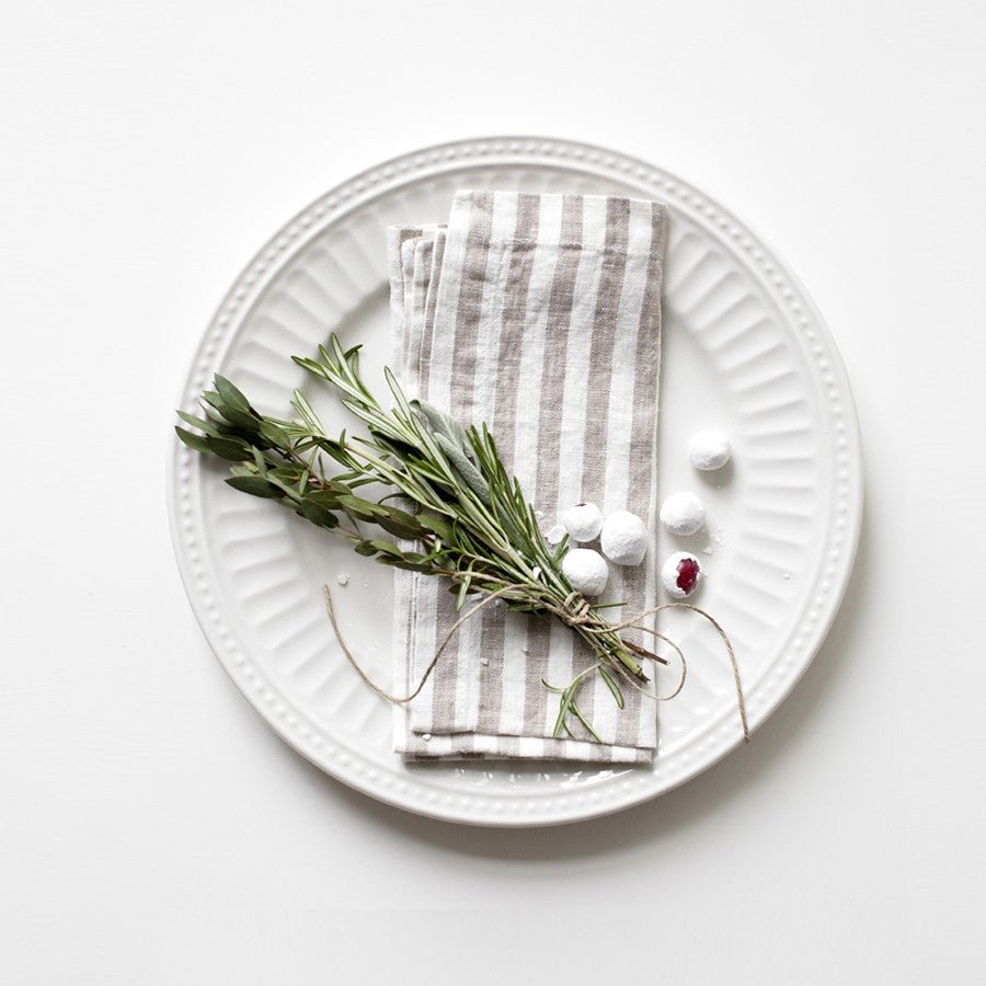 2. Striped linen napkin on a white plate with rosemary and decorative berries on a clean background