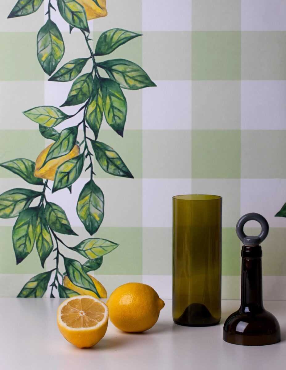 3. Green and brown glass bottles with lemons in front of Lemon Branch wallpaper with leaf and lemon design