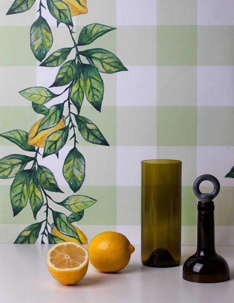 3. Green and brown glass bottles with lemons in front of Lemon Branch wallpaper with leaf and lemon design