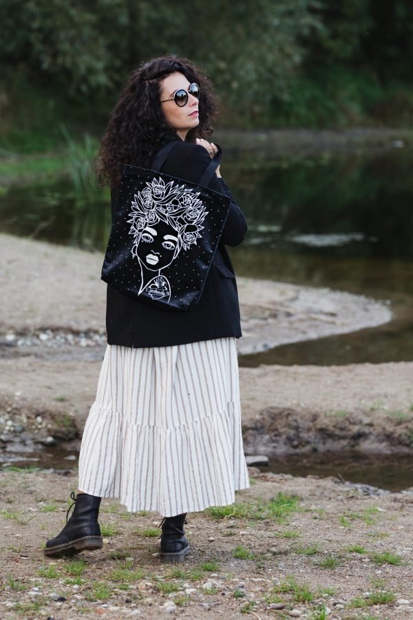 2. Woman outdoors with Garbanota Naomi handbag featuring floral haircut design in black, styled with a long dress
