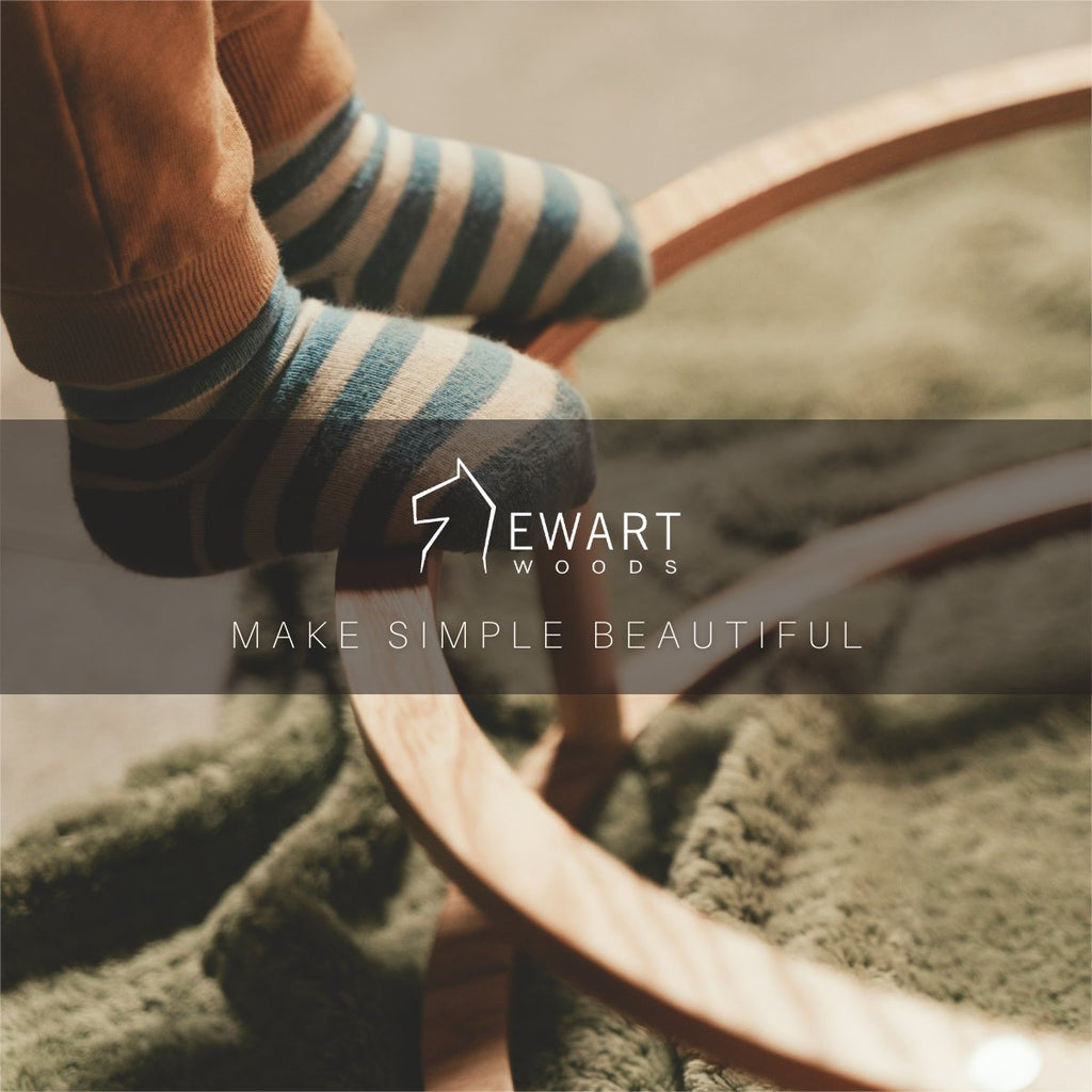 2. Child's feet in striped socks standing on large wooden ring with Ewart Woods logo and 'Make Simple Beautiful' text overlay