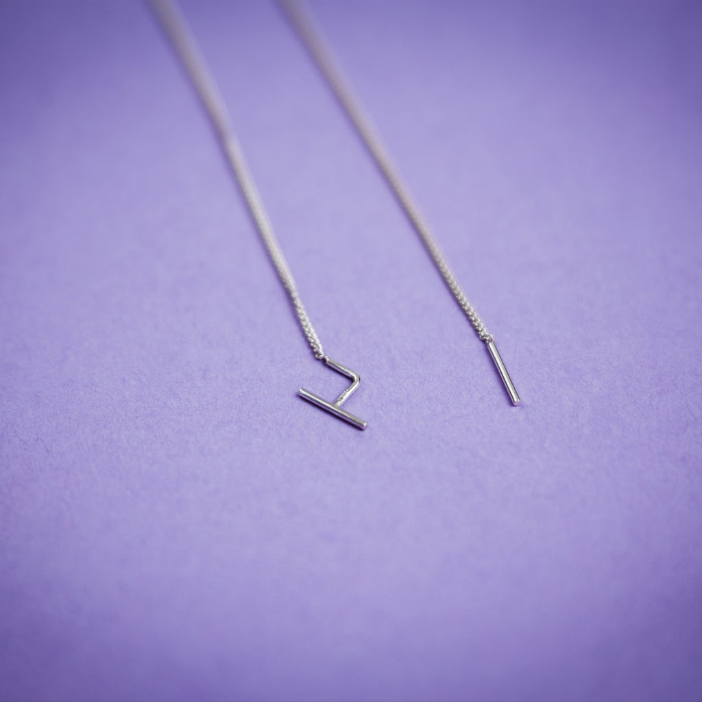 3. Close-up of Maarja Palu SWING earrings with sleek silver chains and bar accents on purple background