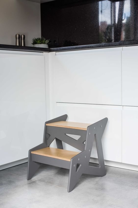 1. Wooden step stool with grey sides and natural wood steps placed in modern kitchen setting