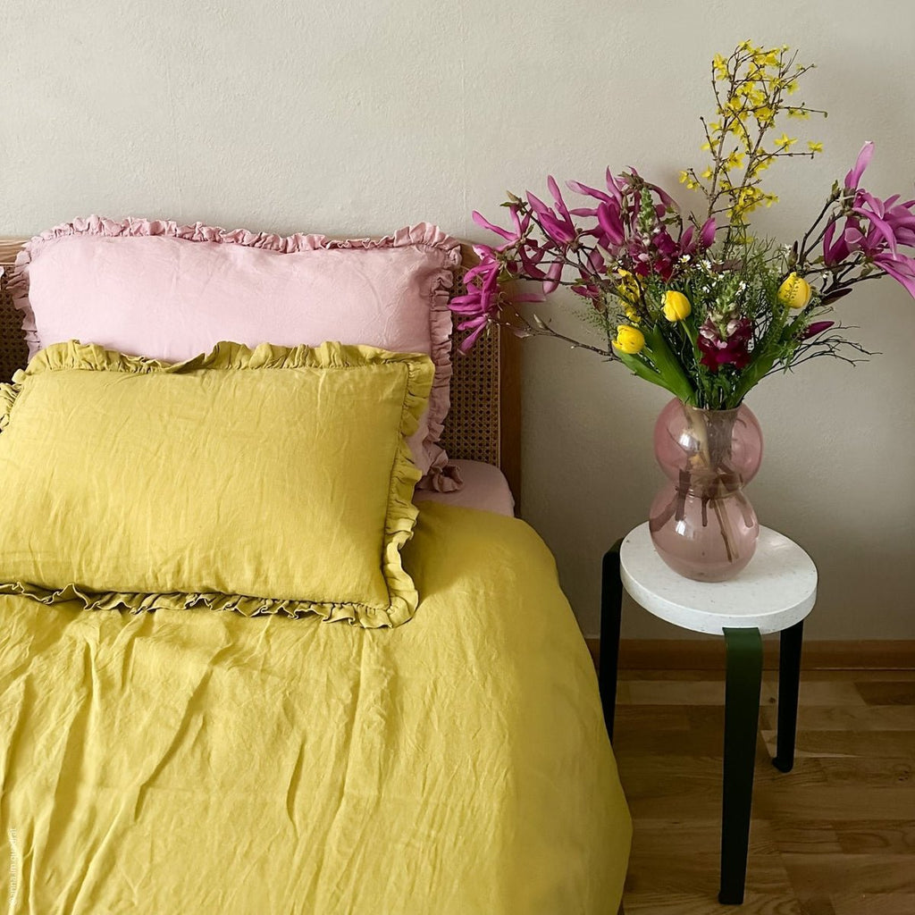 10. Bedroom with yellow and pink frilled linen pillowcases, featuring a vibrant floral arrangement