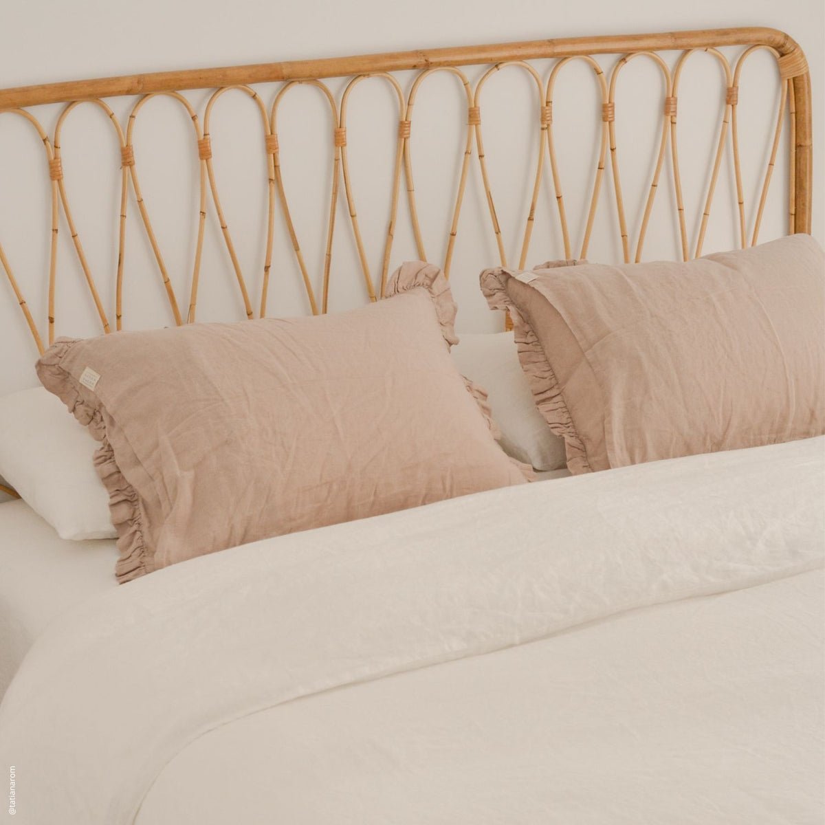 13. Pair of beige frilled linen pillowcases on a bed with a rattan headboard, natural bedroom style